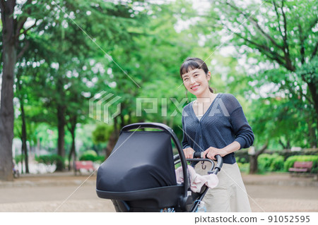 Mom pushing the stroller with a smile Mom pushing the stroller with a smile 91052595
