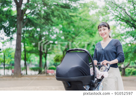 Mom pushing the stroller with a smile Mom pushing the stroller with a smile 91052597