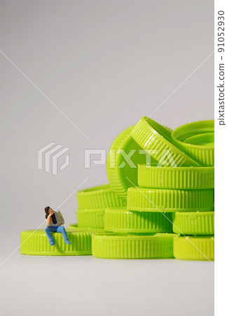 Man figure siting on plastic cap. Recycle material concept. Man figure siting on plastic cap. Recycle material concept. 91052930