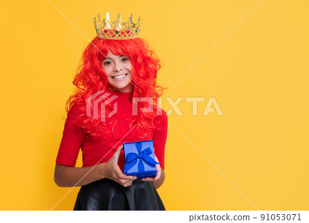 glad child in crown with present box on yellow background 91053071