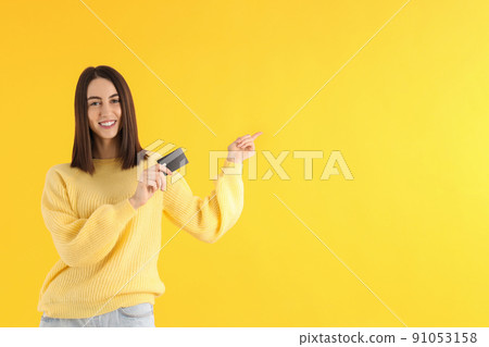 Young attractive girl with card on yellow background 91053158