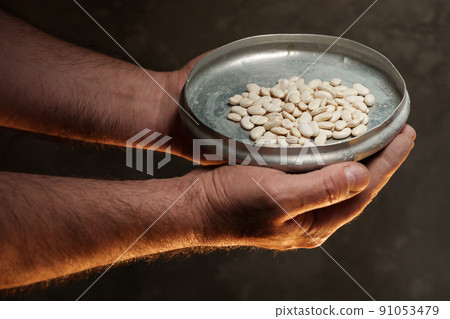 Male hands holding grains of dry kidney beans on dark background 91053479