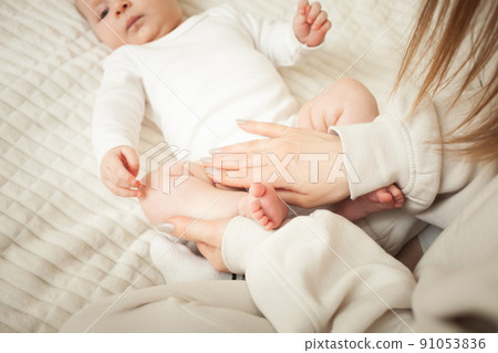 mother massages her little daughter, newborn baby. lies on bed in bedroom, homely. Legs, fingers. care and love mother massages her little daughter, newborn baby. lies on bed in bedroom, homely. Legs, fingers. care and love 91053836
