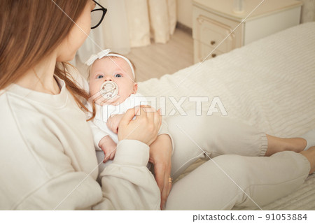 Loving mom carying of her newborn baby at home. portrait of happy mum holding infant child on hands. 91053884