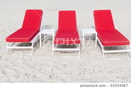 Red deckchairs or sunloungers on sand beach in summer Red deckchairs or sunloungers on sand beach in summer 91054467