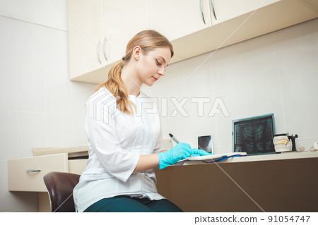 beautiful woman dentist in office, in clinic, indoor. Portrait, smiling and happy. Friendly doctor. makes recordings with pen 91054747