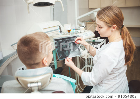 woman doctor shows patient his x-ray of teeth and explains problems. 91054802