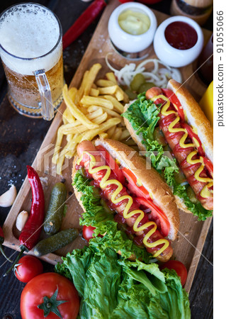 BBQ hot dog served with vegetables and French fries and sauces on wooden serving board 91055066