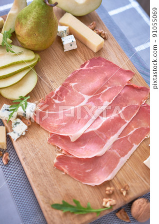 Jamon or prosciutto ham slices, Blue cheese, pears and walnuts on wooden board 91055069