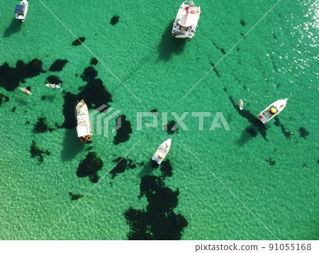 Aerial panoramic view of seascape with crystal clear azure sea and rocky shores. Yachts in a beautiful lagoon on backdrop of rocks. The concept of an ideal destination for summer travel and vacation. 91055168