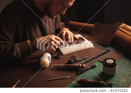 Portrait of handsome tanner man at work, small business, authentic workshop, indoors. leather goods. brown 91055882