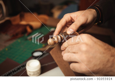wooden tool. tanner makes leather wallet, professional craftsman, closeup, indoors, authentic business Handiwork 91055914