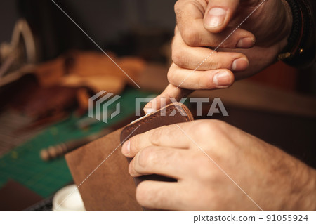 lubricates edges with cream. tanner makes leather wallet, professional craftsman, business. Handiwork. 91055924