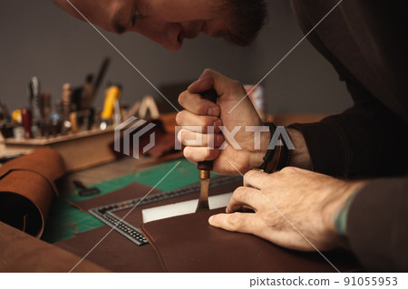 hot tool. tanner makes leather purse. DIY instruction, indoors, closeup, authentic Eco production entrepreneur hot tool. tanner makes leather purse. DIY instruction, indoors, closeup, authentic Eco production entrepreneur 91055953