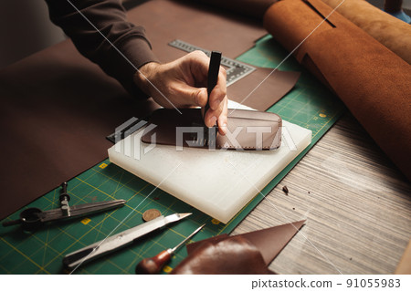 leatherworker punches holes. Tanner works with leather, small business, production. 91055983