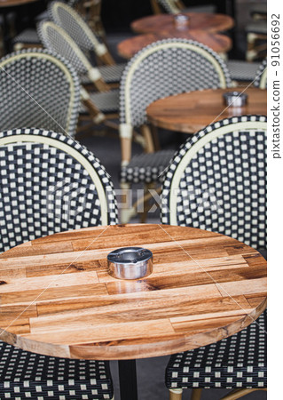 Round wooden table of a street cafe with a metal ashtray - an empty cafe in the morning before receiving visitors for breakfast 91056692