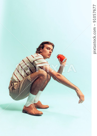 Portrait of young man in retro style outfit, drinking coke, posing isolated over light blue studio background. Resting Portrait of young man in retro style outfit, drinking coke, posing isolated over light blue studio background. Resting 91057677