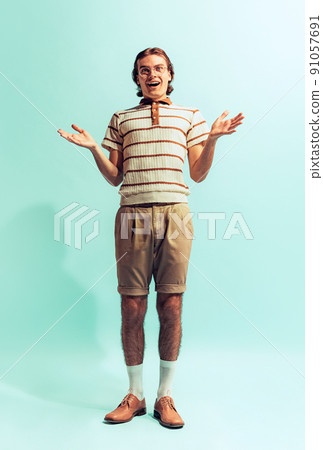 Full-length portrait of young delightful man in retro style outfit posing isolated over light blue studio background Full-length portrait of young delightful man in retro style outfit posing isolated over light blue studio background 91057691