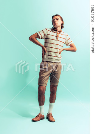 Full-length portrait of young man in retro style outfit posing isolated over light blue studio background Full-length portrait of young man in retro style outfit posing isolated over light blue studio background 91057693