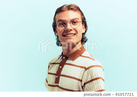 Portrait of young cheerful man in sjtylish glasses posing, smiling at camera isolated over light blue studio background Portrait of young cheerful man in sjtylish glasses posing, smiling at camera isolated over light blue studio background 91057721