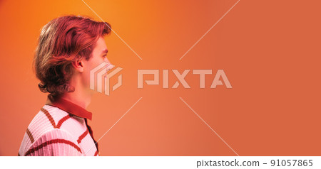 Side view portrait of young handsome man posing, looking away isolated over orange studio background in neon light. Flyer Side view portrait of young handsome man posing, looking away isolated over orange studio background in neon light. Flyer 91057865