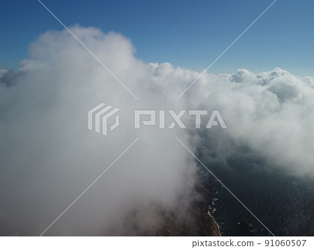 Aerial view. The drone flies over foggy and fluffy clouds. Blue sky sun and sea fog. Abstract aerial nature summer ocean sunset sea and sky background. Vacation, vacation and holiday concept 91060507