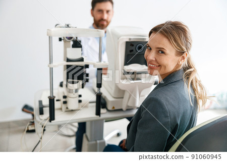 Smiling woman patient awaits a vision test at opticians shop or ophthalmology clinic 91060945