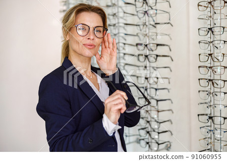 Businesswoman chooses a spectacle frame in an optician's shop Businesswoman chooses a spectacle frame in an optician's shop 91060955