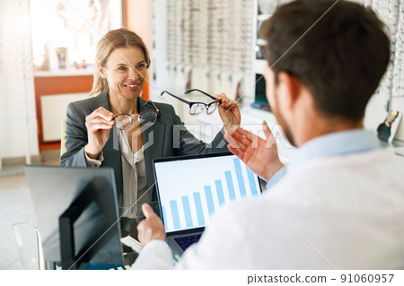 An ophthalmologist consults a client at his workplace in an optician's shop 91060957