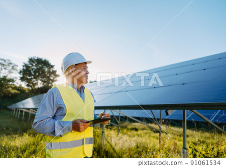Male engineer using tablet to inspect the solar panels. Eco energy concept Male engineer using tablet to inspect the solar panels. Eco energy concept 91061534