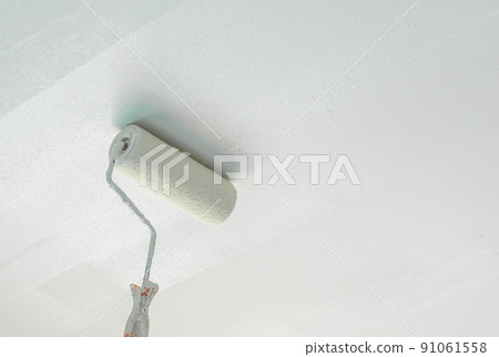 painting a gypsum plaster ceiling with paint roller 91061558