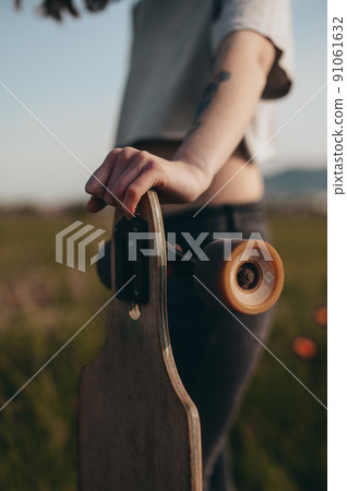 detail of a girl leaning on a longboard. anonymous photography. faceless . Sunny day . 91061632