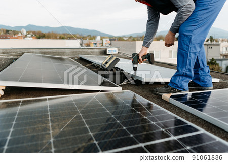 Man worker installing solar photovoltaic panel system using screwdriver. Alternative energy concept Man worker installing solar photovoltaic panel system using screwdriver. Alternative energy concept 91061886