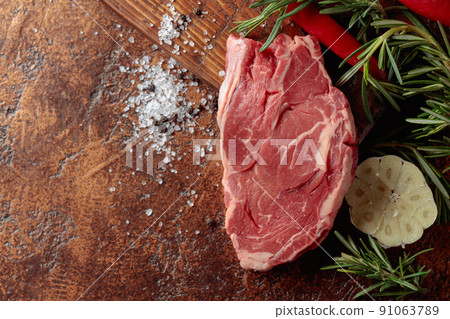 Raw beef meat steak with rosemary, garlic, salt, and pepper. Raw beef meat steak with rosemary, garlic, salt, and pepper. 91063789