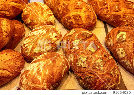 Fresh bread with crispy crust in the bakery top view. Freshly baked goods closeup. 91064020