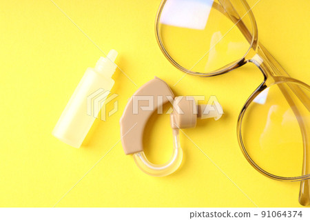 Concept of health care with hearing aid on yellow background Concept of health care with hearing aid on yellow background 91064374
