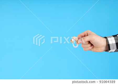 Male hand holds hearing aid on blue background 91064389