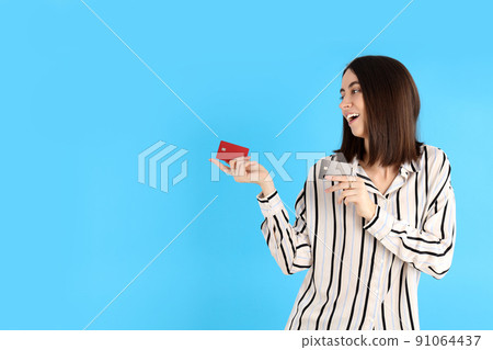 Attractive woman with cards on blue background Attractive woman with cards on blue background 91064437