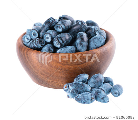 Honeysuckle berries in wooden bowl, isolated on white background. Ripe berries of honeysuckle. Clipping path. 91066092