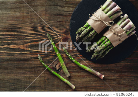 An edible, raw stems of asparagus on a wooden background. An edible, raw stems of asparagus on a wooden background. 91066243