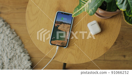 Top view. Hands of woman plugging charging cable in mobile phone. 91066252