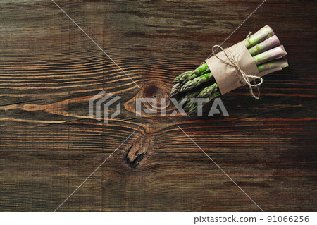 An edible, raw stems of asparagus on a wooden background. An edible, raw stems of asparagus on a wooden background. 91066256