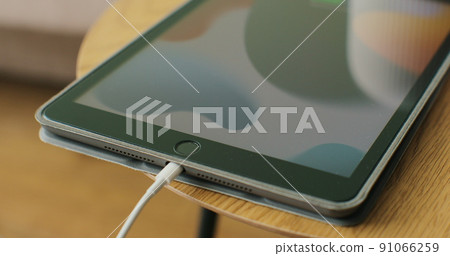 Woman hand plugging charging cable into pc digital tablet. Close up shot. Woman hand plugging charging cable into pc digital tablet. Close up shot. 91066259