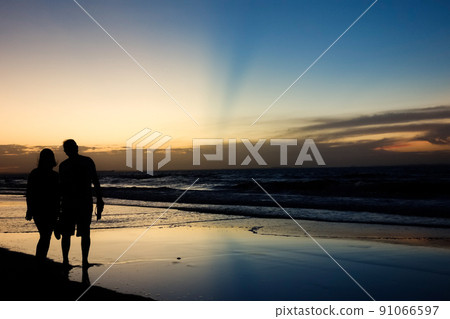 romantic couple silhouette on sunset with colors reflecting in the sky and the sea 91066597