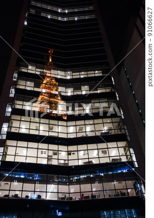 illuminated tower reflected on windows of building facade, at night illuminated tower reflected on windows of building facade, at night 91066627