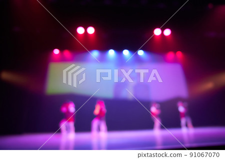 Blurred background of a dance scene with silhouettes of children dancing and a screen in the background. Bright stage lighting. Lighting devices on stage. High quality photo 91067070