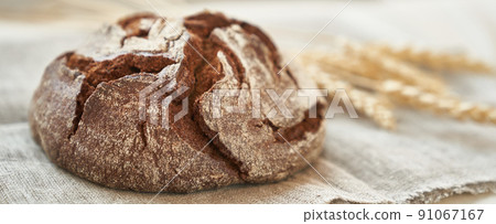 Freshly baked rye bread on a yeast-free starter and on a mixture of whole grain, rye and wheat flour. It lies on a napkin, next to a dried flower with grains. Selective focus. High quality photo Freshly baked rye bread on a yeast-free starter and on a mixture of whole grain, rye and wheat flour. It lies on a napkin, next to a dried flower with grains. Selective focus. High quality photo 91067167