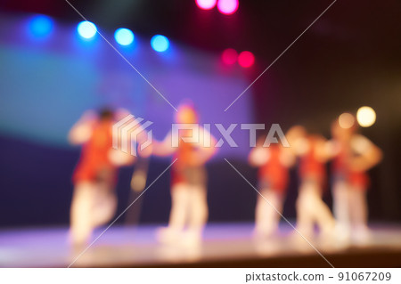A colored blurry background of a dance festival from a group of little girls. Bright stage lighting. Silhouettes of little dancers. High quality photo 91067209