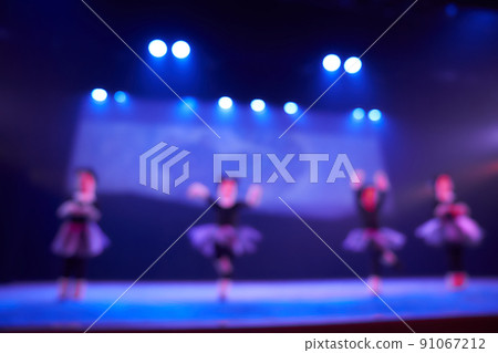 A blurry abstract background of a dance festival from a group of girls in the number of four people. Bright lighting of the blue dance floor stage. High quality photo 91067212