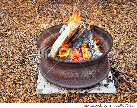 Campfire in a steel wheel on the concrete base 91067556